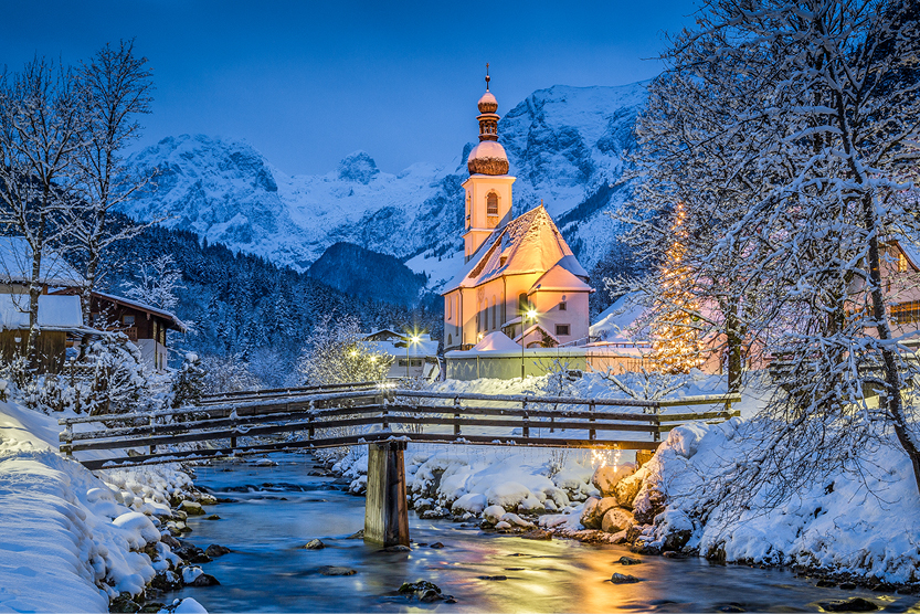 Kirche in weihnachtlich festlicher, verschneiter Berglandschaft